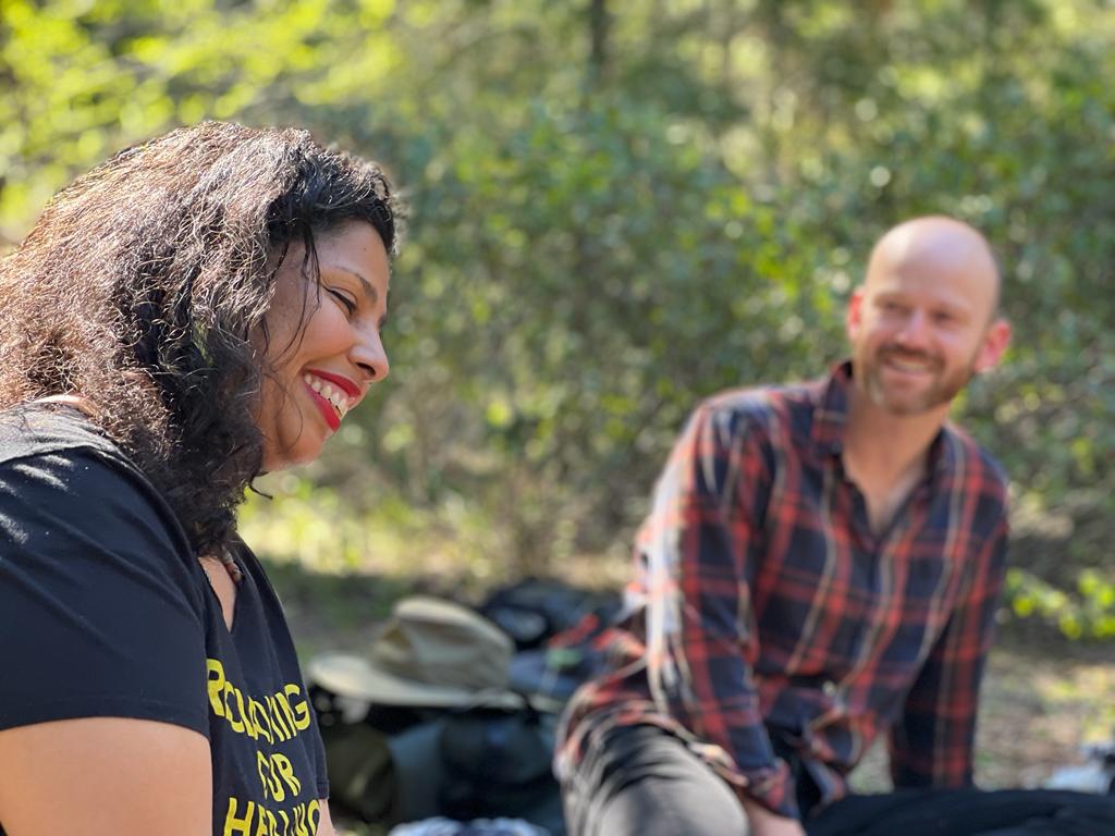 Two students talking and laughing together outdoors in the forest