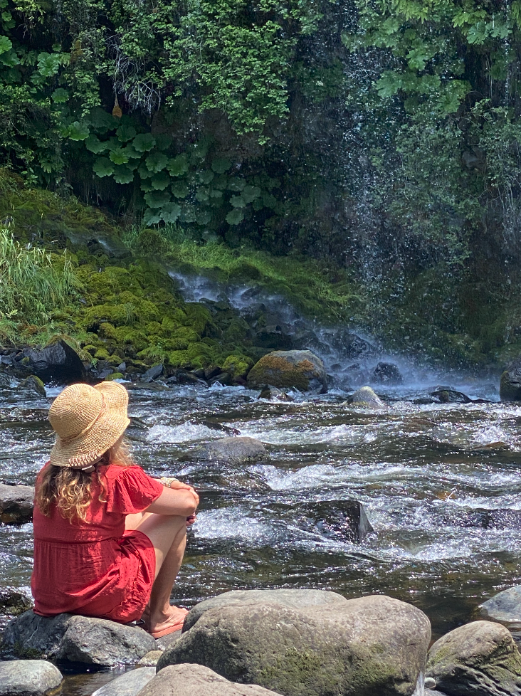 A person in red sitting beside a river